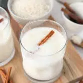 Close-up view of Mexican horchata in a cup with ice and a cinnamon stick.