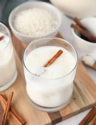 Close-up view of Mexican horchata in a cup with ice and a cinnamon stick.