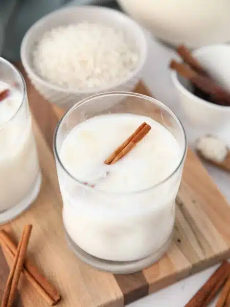 Close-up view of Mexican horchata in a cup with ice and a cinnamon stick.