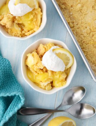 Lemon Dump Cake in a small bowl topped with whipped topping and a lemon slice.