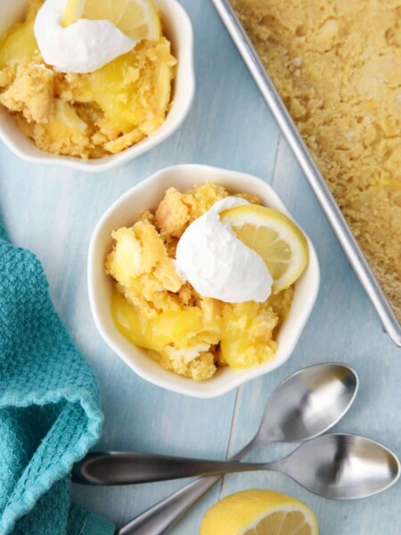 Lemon Dump Cake in a small bowl topped with whipped topping and a lemon slice.