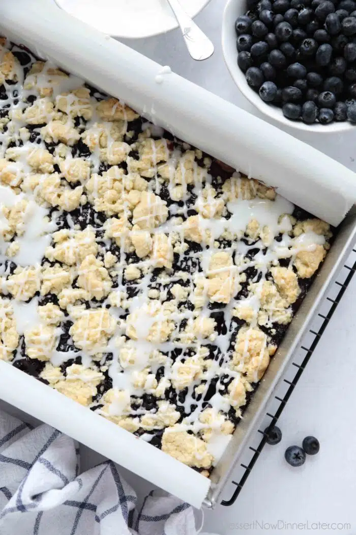 Pan of blueberry pie bars with glaze on top.