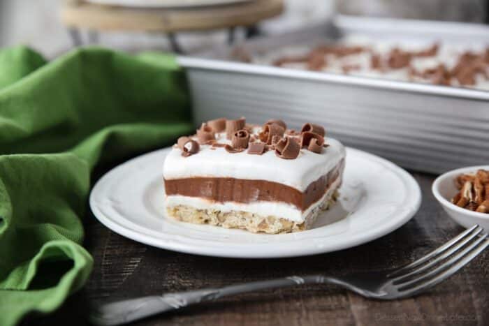 Layered dessert with a pecan crust topped with layers of cream cheese, chocolate pudding, and Cool Whip topped with chocolate curls for decoration.