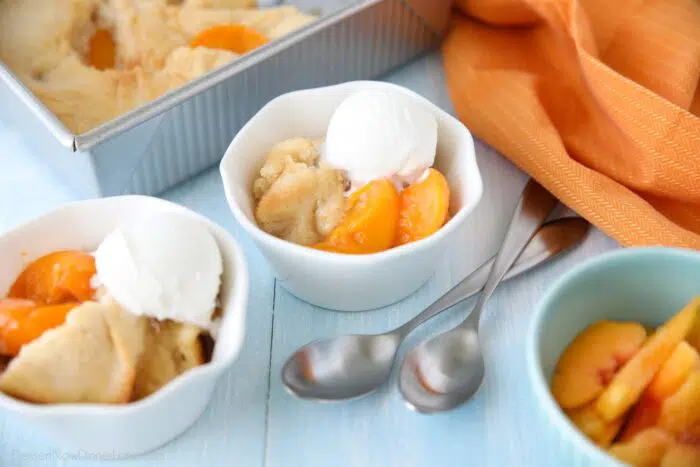 Peach Cobbler with cake batter crust on top and a scoop of vanilla ice cream.