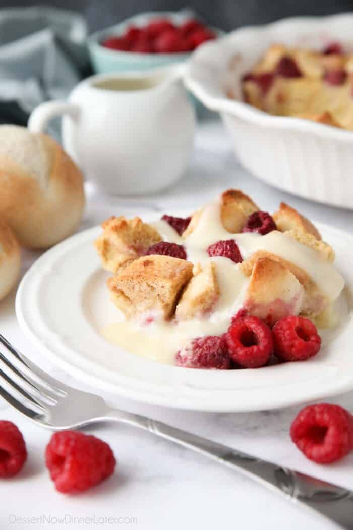 Raspberry Bread Pudding on plate with vanilla cream sauce and fresh raspberries.