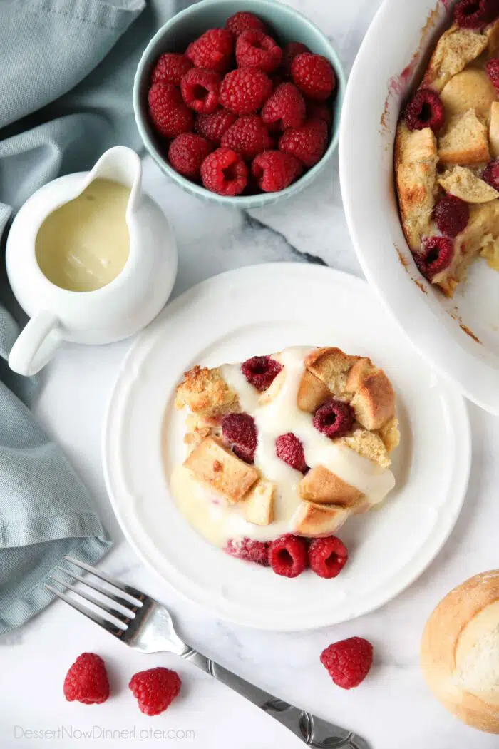 Plated raspberry bread pudding with vanilla cream sauce.