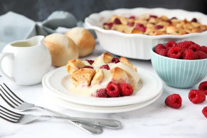 Bread pudding on plate with raspberries and vanilla sauce.