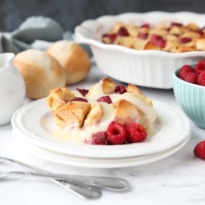 Bread pudding on plate with raspberries and vanilla sauce.