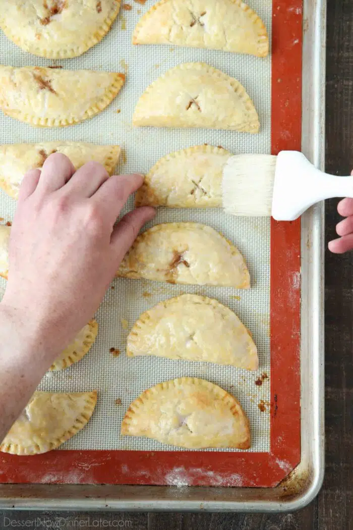 Brushing glaze onto mini apple pies.