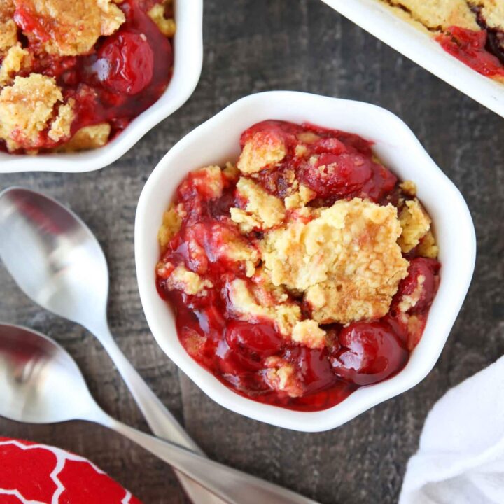 Bowl full of cherry dump cake made with cherry pie filling, cake mix, and butter.