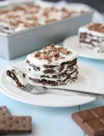 Icebox Cake with layers of chocolate graham crackers and whipped cream with chocolate curls on top.