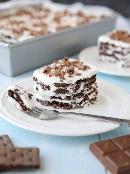 Icebox Cake with layers of chocolate graham crackers and whipped cream with chocolate curls on top.