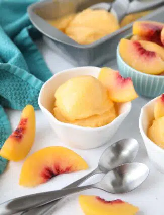 Peach Sorbet made with frozen peaches, sugar and lemon juice, scooped into a dish.
