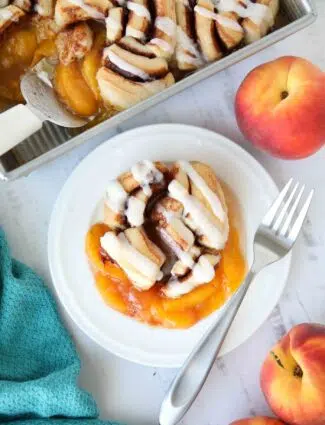 Cinnamon Roll Peach Cobbler on a plate with a fork.