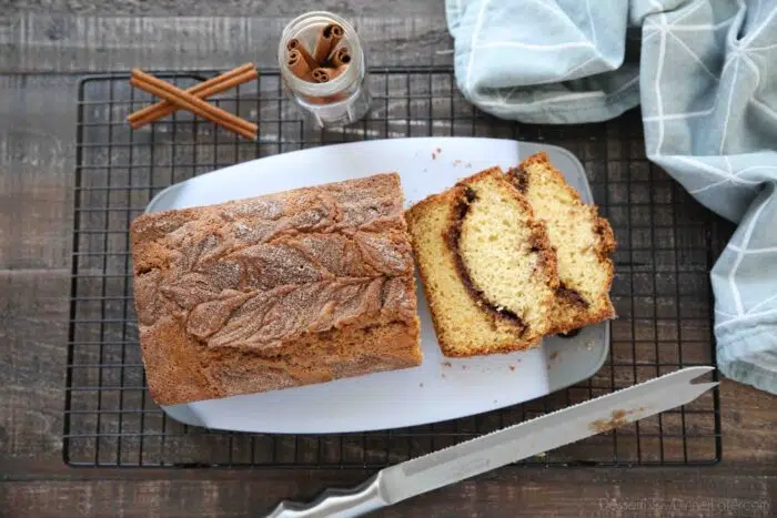 Top view of cinnamon quick bread being sliced on a cutting board.