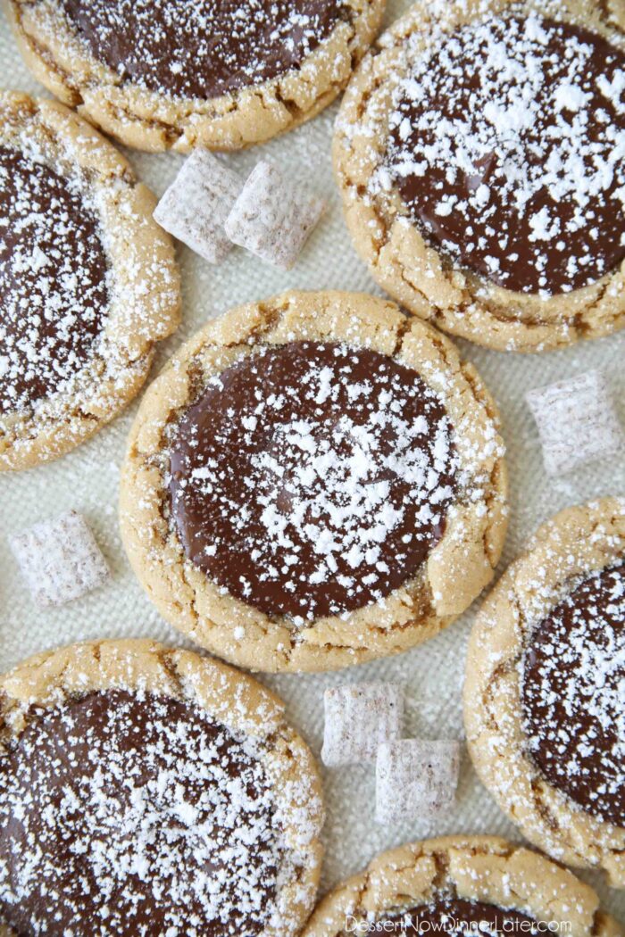 Close-up de Muddy Buddy Cookies - biscoitos de manteiga de amendoim cobertos com chocolate derretido e polvilhados com açúcar de confeiteiro.