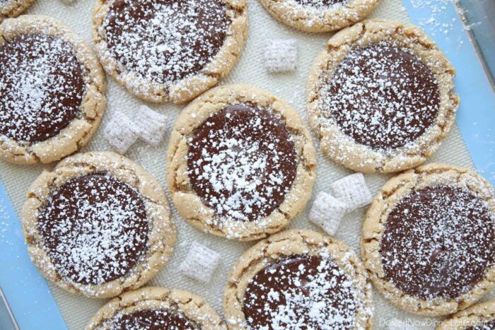 Peanut butter cookies topped with melted chocolate and sprinkled with powdered sugar to be like muddy buddies.