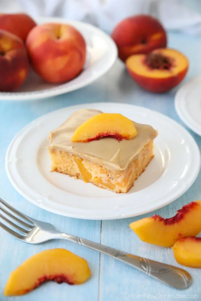 A square piece of peach cake with brown sugar frosting on a plate.