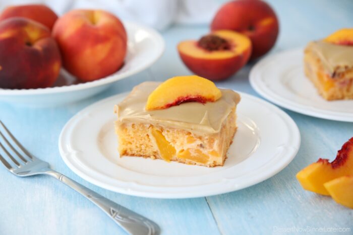 A square piece of peach cake with brown sugar frosting on a plate.