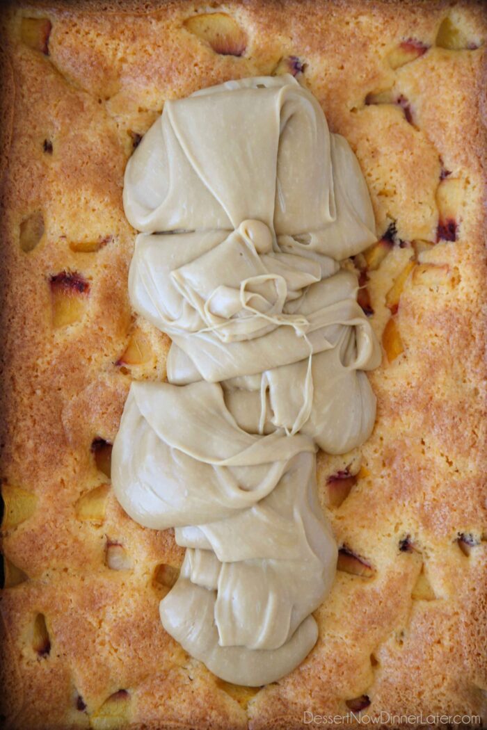 Brun farin frosting hældt ovenpå en friskbagt ferskenkage.