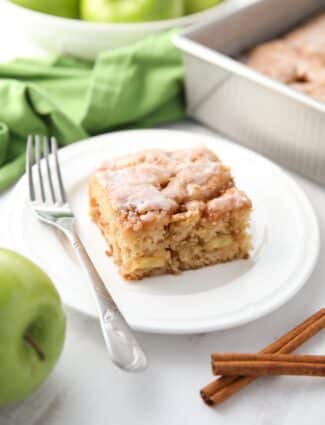 Square piece of glazed apple fritter cake on a plate.