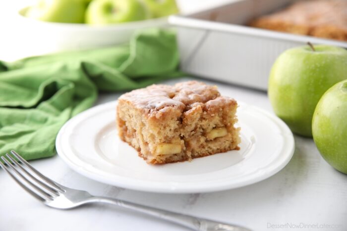 Četvrtasti komad glazirane torte od jabuka na tanjuru.