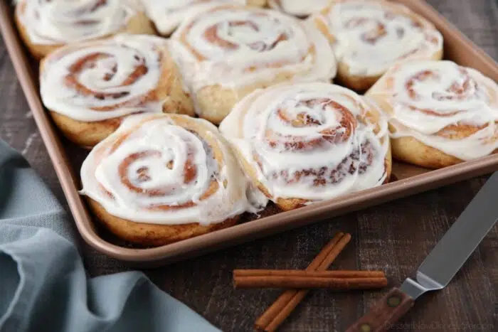 The best cinnamon rolls in a pan with cream cheese frosting on top.