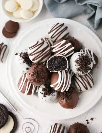 Chocolate covered Oreo Balls on a plate with one cut open to see the inside.