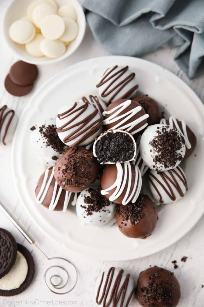 Chocolate covered Oreo Balls on a plate with one cut open to see the inside.