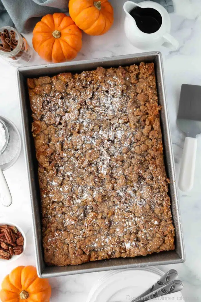 Baked pumpkin French toast casserole in a pan with powdered sugar on top.