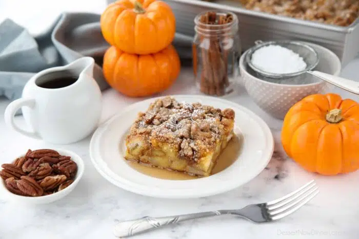Square piece of pumpkin French toast casserole on a plate with syrup and powdered sugar.