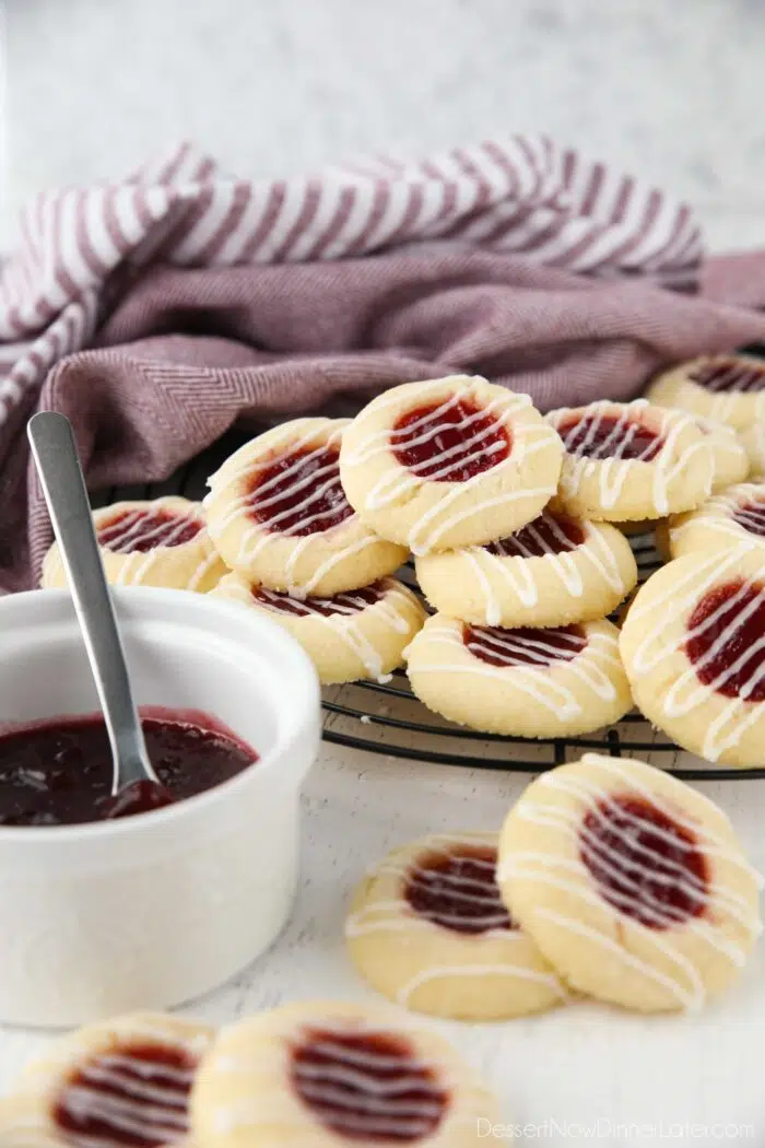 Thumbprint cookies stacked on top of a wire cooling rack.