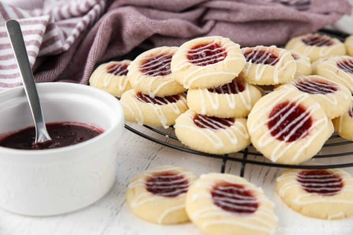 Thumbprint cookies stacked on top of a wire cooling rack.