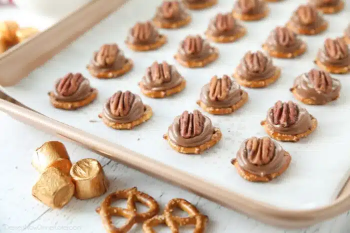 Rolo Pretzel Turtles on a baking sheet.