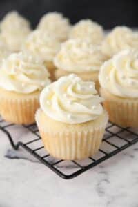 White Cupcakes with vanilla frosting and white sugar pearls on top.