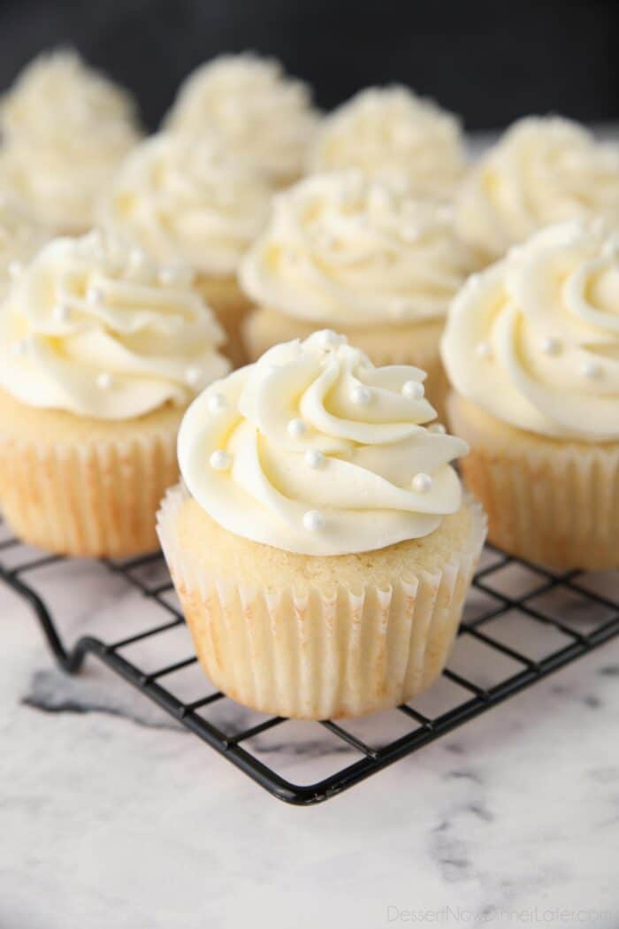 White Cupcakes with vanilla frosting and white sugar pearls on top.