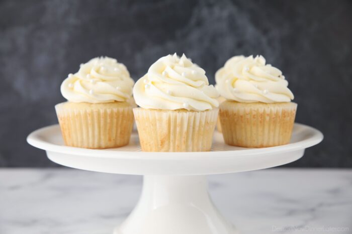 Dekorerede hvide cupcakes på et kagefod.