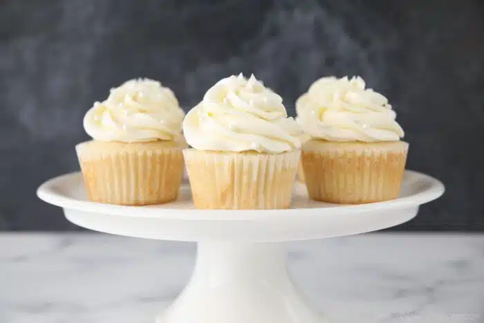 Decorated white cupcakes on a cake stand.