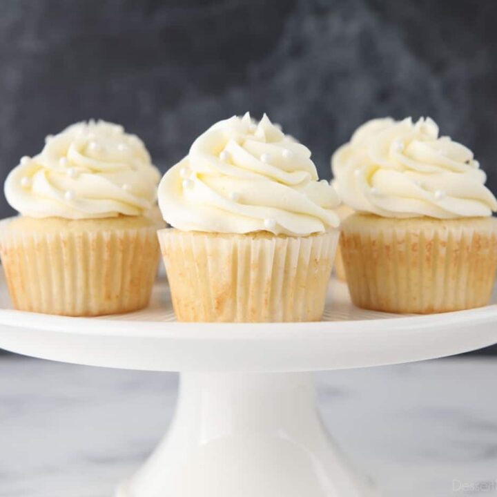 Decorated white cupcakes on a cake stand.