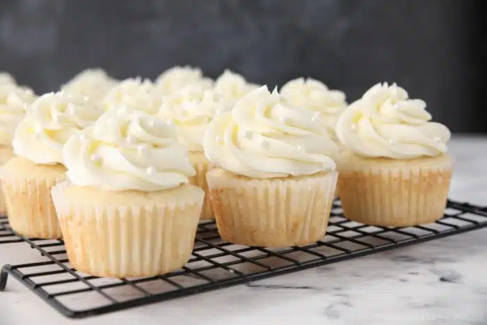 Decorated white cupcakes on a wire rack.