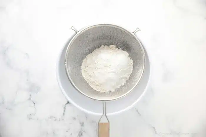 Dry ingredients being sifted into a bowl.