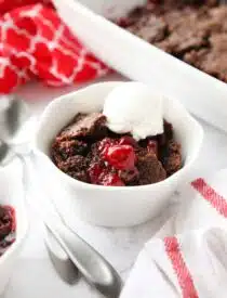 Chocolate cherry dump cake in a small bowl topped with vanilla ice cream.
