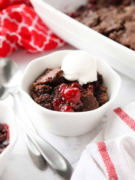Chocolate cherry dump cake in a small bowl topped with vanilla ice cream.