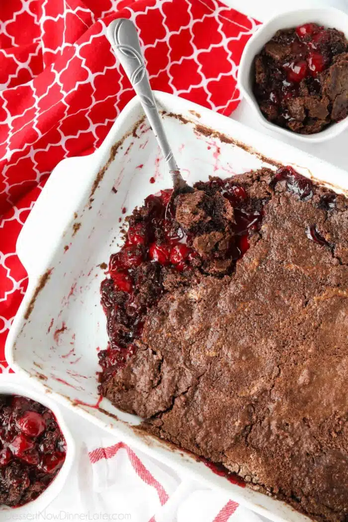 Baked chocolate cherry dump cake in baking dish with a serving spoon.