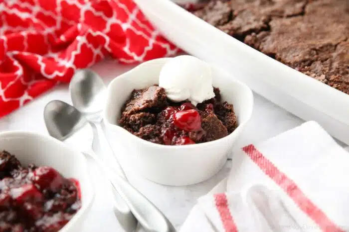 Chocolate cherry cobbler in a small bowl topped with vanilla ice cream.