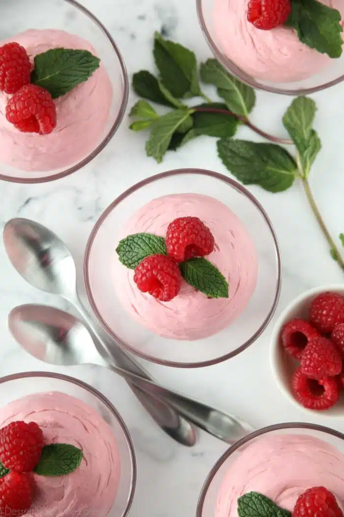 Top view of Raspberry Mousse in a small clear bowls with fresh raspberries and mint on top.