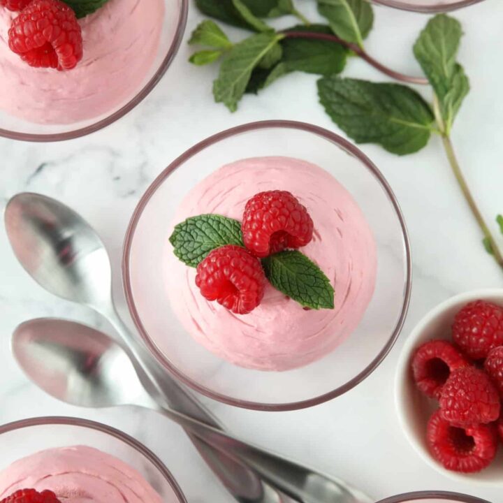 Top view of Raspberry Mousse in a small clear bowls with fresh raspberries and mint on top.