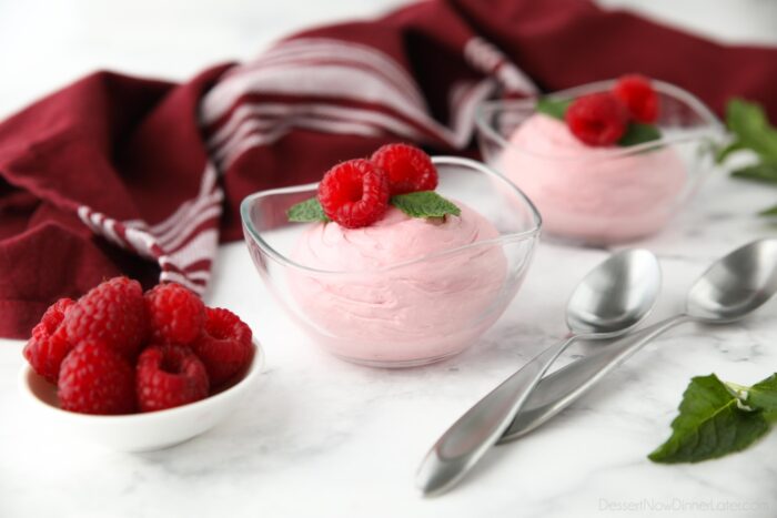 Raspberry Mousse in a small clear bowl with fresh raspberries and mint on top.