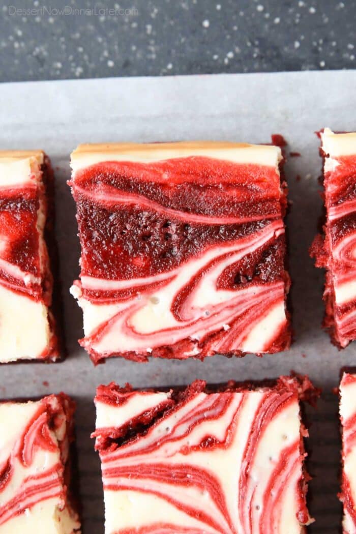 Squares of red velvet brownies with cheesecake swirled on top.