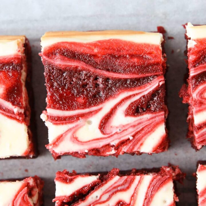 Squares of red velvet brownies with cheesecake swirled on top.
